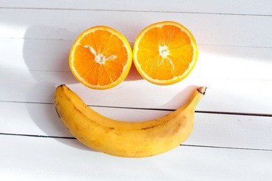 smiling face made from fruit on a wooden background. fruit smile. two halves of oranges, and one banana. vitamins for a good mood