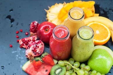 fresh juices smoothie three bottles red green orange tropical fruits water melon strawberry apple kiwi grapes orange mango banana pine apple pomegranate grape selective focus