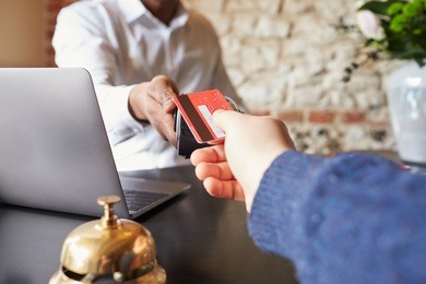 guest makes card payment at check-in desk of hotel, detail