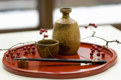 chopsticks and japanese sake cup and bottle on a tray.