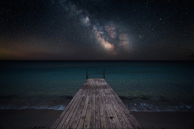 milky way over che seashore and small wooden jetty in perspective
