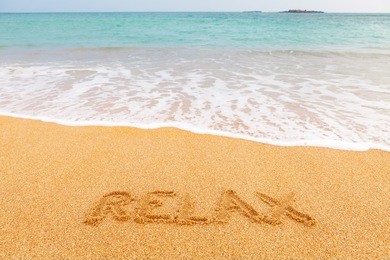inscription "leisure" made on beautiful beach by the blue sea