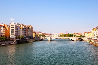 view on sunlit bridge over calm river in lyon, france