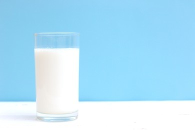 glass of milk on white wooden table. minimal concept.