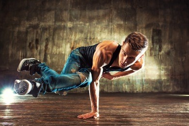 young man break dancing on old wall background