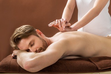 portrait of a young man receiving back massage at a beauty spa