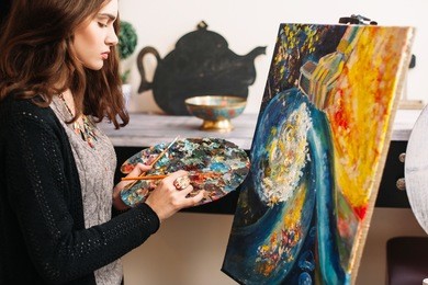 creative contemporary painter paints a colorful abstract painting. closeup of painting process in art workshop. creative positive woman painter paints in her studio colorful abstract painting 