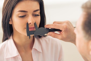 doctor is examining beautiful young woman's face using a special equipment