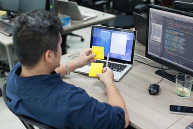 asian business man yellow sticky note, rear back view thinking idea computer developer working desk laptop sitting real office