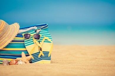 flip-flops and bag on sandy beach against blue sea and sky background. summer vacation concept