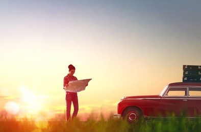 toward adventure! beautiful young woman checks the route on a map on the sunset background.