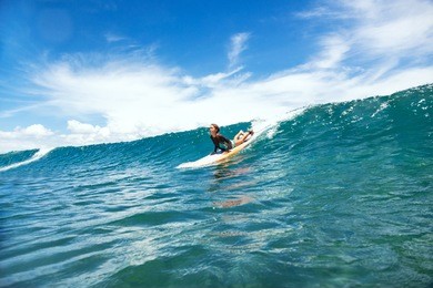 kid girl is learning surfing, riding a wave