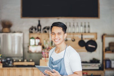 portrait of small business owner at his coffee shop using tablet pc
