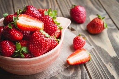 fresh strawberries in a bowl on wooden table with low key scene.