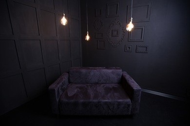 black sofa in a dark room with light bulb