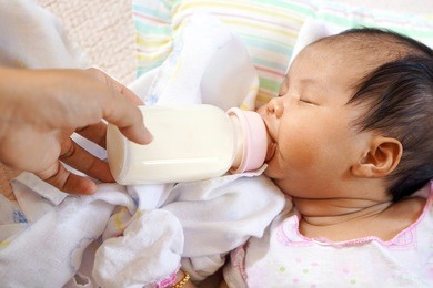  asian newborn baby drinking milk from bottle                            