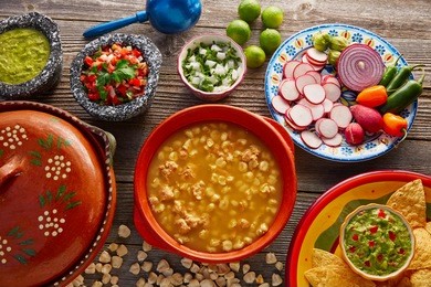 green pozole verde with blanco mote corn and ingredients on wooden table