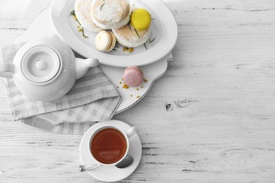 cup of tea with macaroons on wooden background