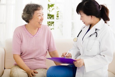 nurse making notes during home visit with senior woman