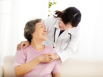 nurse holding hand of senior woman in rest home