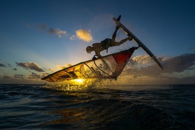 professional athlete doing incredible trick at windsurfing on the background of a picturesque sunset and spray. mauritius, indian ocean