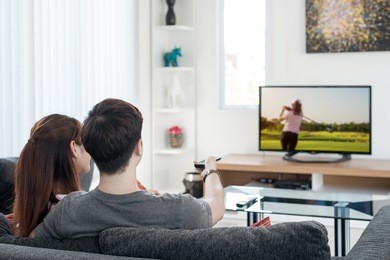 young asian couple watching golf sport on tv at home. enjoy golf sport game.