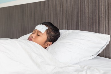 children with white cool fever on forehead and sleeping on the bed