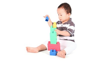 cute toddler playing with block toys, isolated on white background