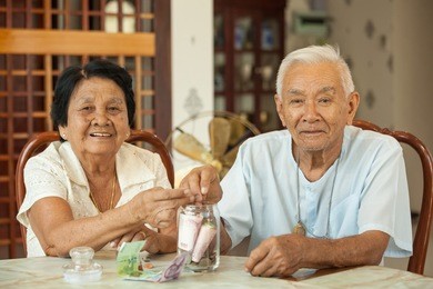 senior couple counting money with glass bank