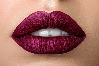 close up view of beautiful woman lips with purple matt lipstick. open mouth with white teeth. cosmetology, drugstore or fashion makeup concept. beauty studio shot. passionate kiss