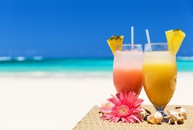 two tropical fresh juices on white sandy beach
