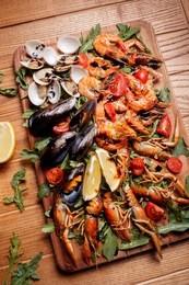 fresh mussels, crayfish, shrimp decorated with arugula, tomatoes, lemon and sauce on a wooden board. seafood platter