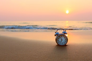 alarm clock vintage with sunrise on beach