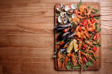 fresh mussels, crayfish, shrimp decorated with arugula, tomatoes, lemon and sauce on a wooden board. seafood platter