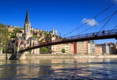 pedestrians on the saint georges footbridge and the saint georges church in lyon, france.