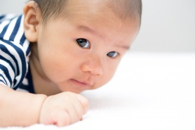 asian baby lying on stomach and raising his head