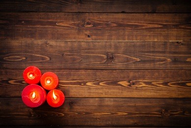 four red candles on brown wooden table, top view