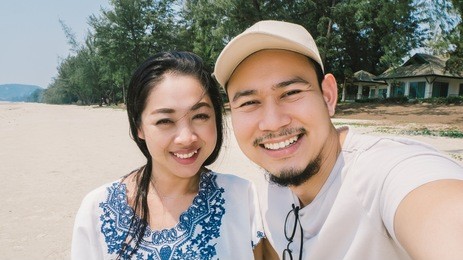 asian couple is taking selfie on random beach of thailand.