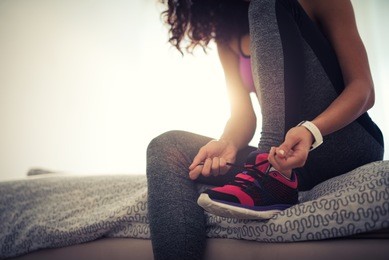 woman tying a shoelace and preparing for fitness.