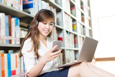 young beautiful asian girl university student with laptop and mobile phone in library