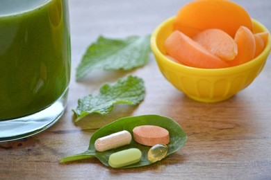 green detox smoothie, dietary supplements and a serving of apricots on wooden table