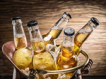 cold bottles of beer in the brazen bucket on the wooden table.