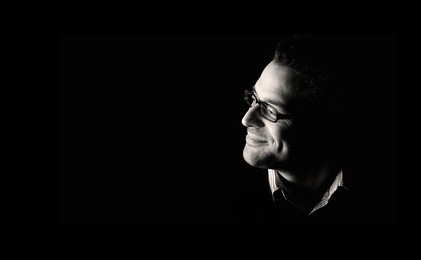 close-up of young confident and happy man, low key, black and white