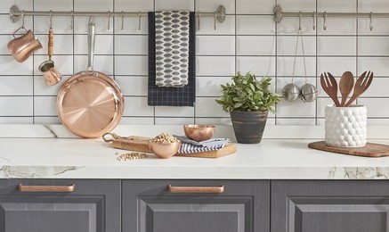kitchen brass utensils, chef accessories. hanging copper kitchen with white tiles wall