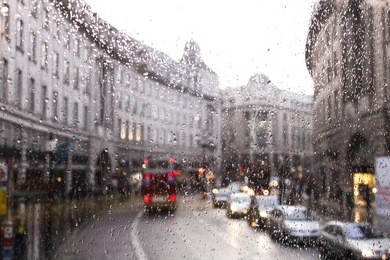 blurred view of road traffic in london on a rainy day through the bus window. raindrops on the glass window of the bus.