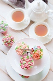 cakes and macaroons on two tiered tray with teapot and cup background. afternoon tea