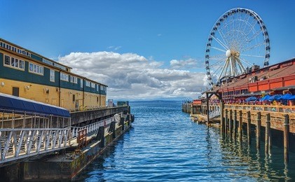 looking down the docks of the pier district in seattle, washington with the great wheel in the distance