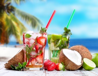 mojito lime and strawberry drinks on wood with blur beach background
