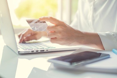 woman's hands holding a credit card and using laptop for online shopping