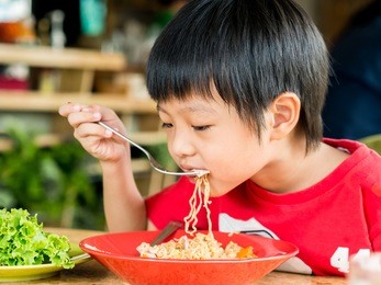 happy asian boy eating delicious noodle